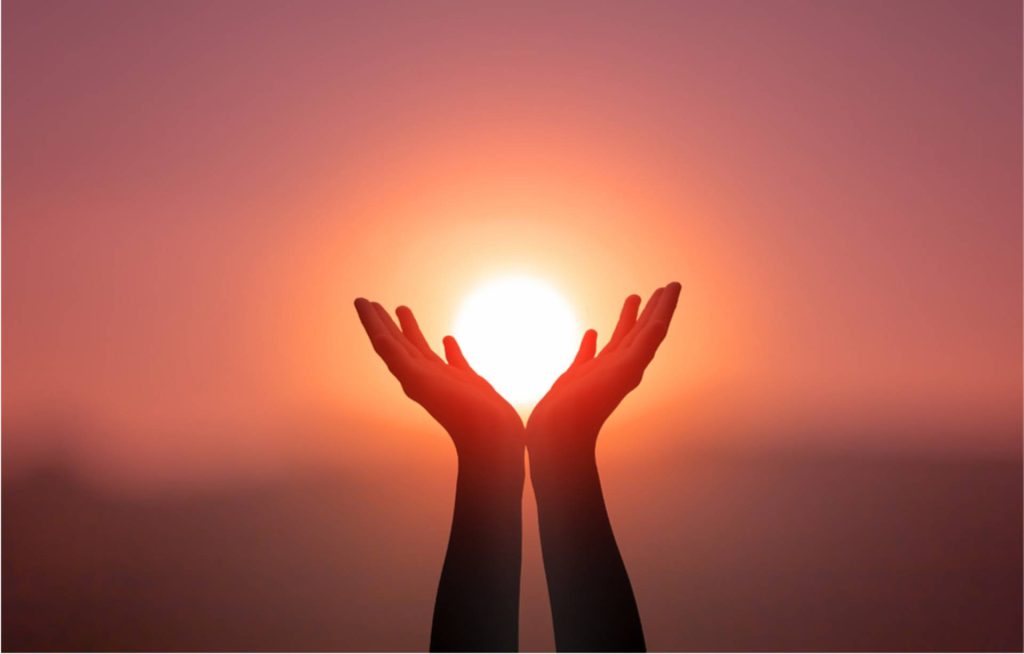 Silhouette of hands raised toward the sun, representing faith, gratitude, and spiritual connection through yoga.